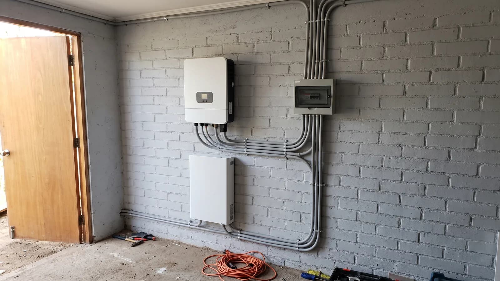 Inversor híbrido con batería de litio y tablero eléctrico instalados en un garaje